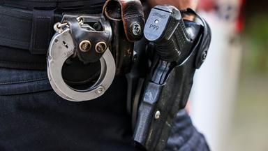 Ein Polizeibeamter trägt seine Dienstwaffe Walther P99 und Handschellen