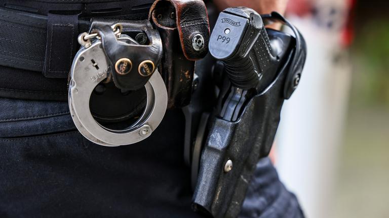 Ein Polizeibeamter trägt seine Dienstwaffe Walther P99 und Handschellen