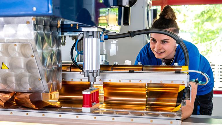 Annemarie steht im Betrieb am Schweißgerät.