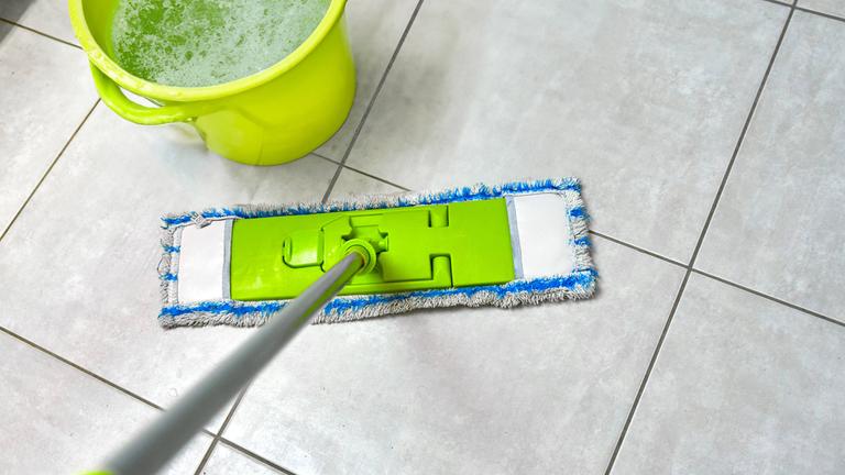 Wischmopp mit Wassereimer auf Fliesenboden
