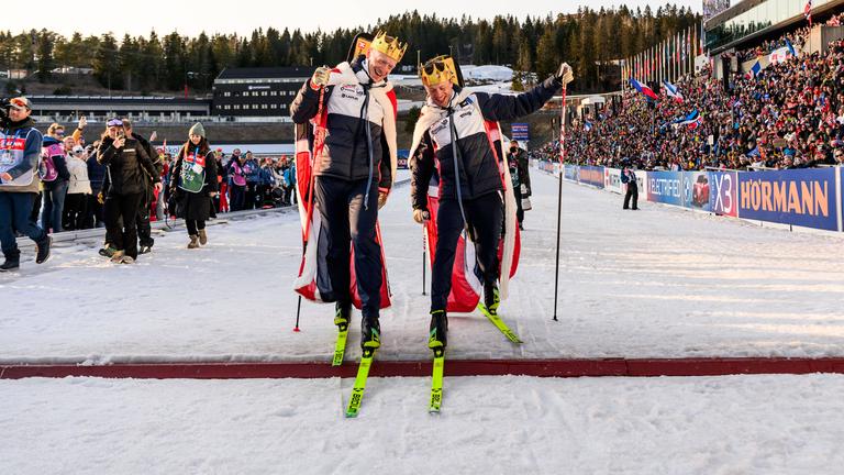 Johannes Thingnes und Tarjei Bö fahren nach dem Massenstart am 23.3.25 am Holmenkollen ein letztes Mal demonstrativ über die Ziellinie, beide mit Krone-Attrappen auf dem Kopf