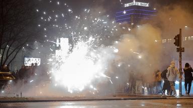Silvesterböller explodieren in Berlin während Passanten vorbeigehen.