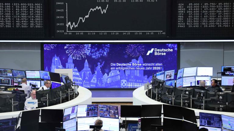 Traders sit in front of a board displaying the chart of Germany's share index DAX at the stock exchange in Frankfurt am Main, western Germany, on the last day of 2025 trading.
