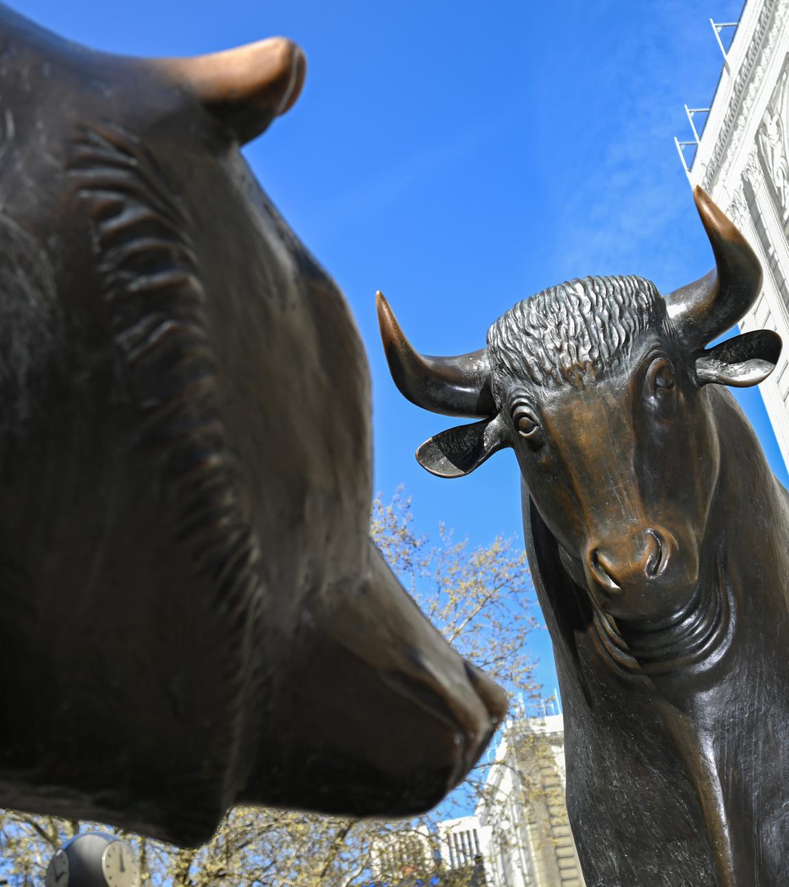 Die Bronzefiguren von Bulle (r) und Bär, Symbole für den Börsenauf- und abschwung, stehen auf dem Platz vor der Börse. 