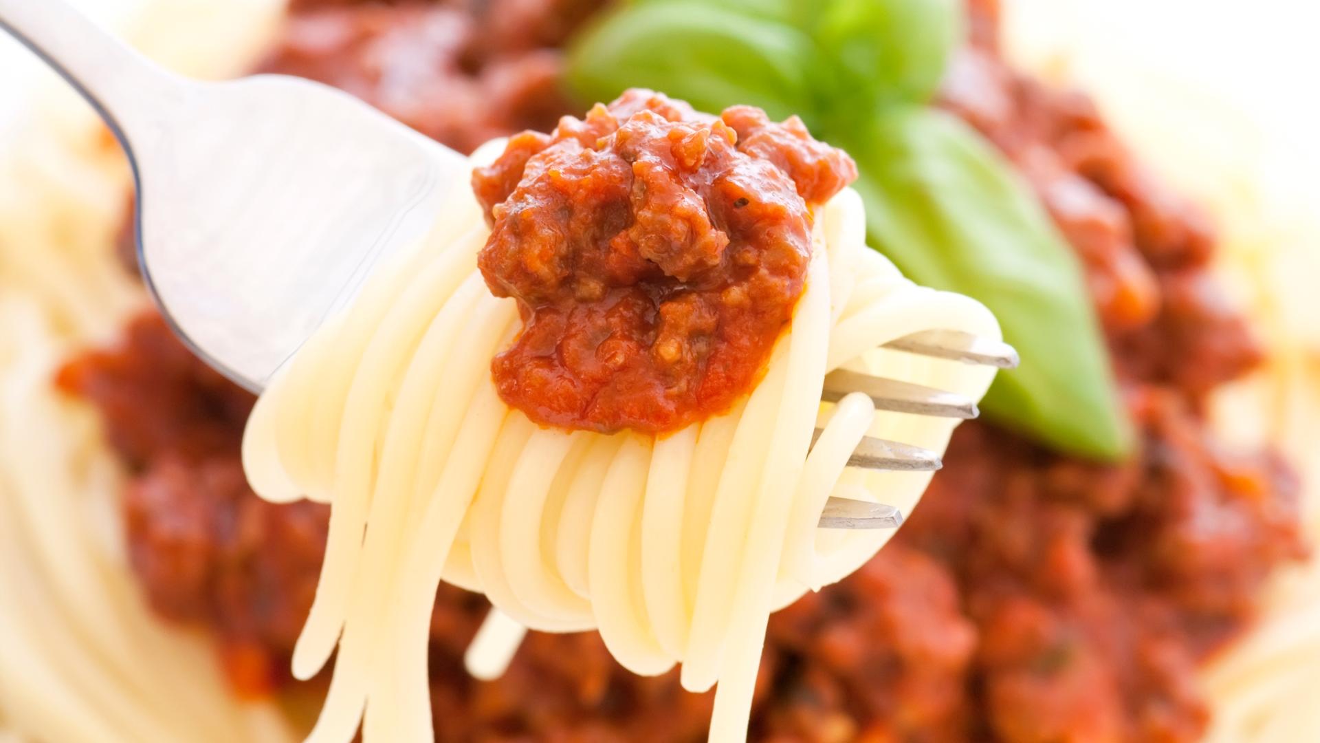 Spaghetti mit bolognese Soße als Nahaufnahme auf einer Gabel.