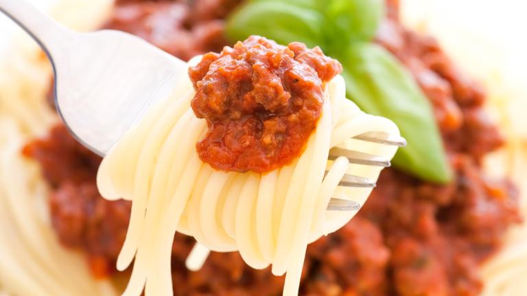 Spaghetti mit bolognese Soße als Nahaufnahme auf einer Gabel.
