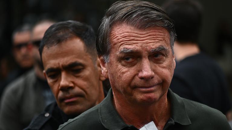 Eine Aufnahme von Bolsonaro nachdem er das Krankenhaus verlässt. Er schaut ernst in die Kamera.