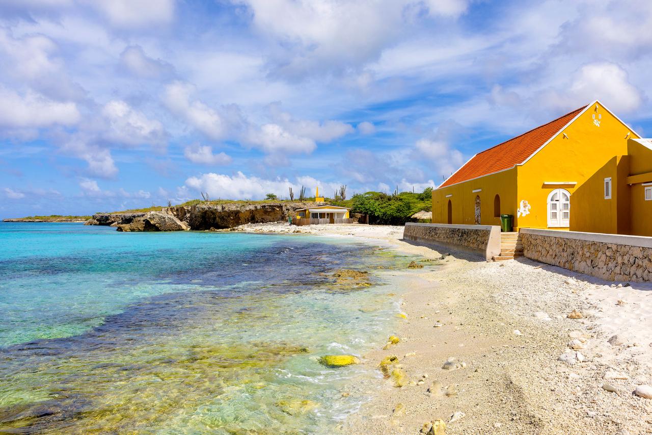 Bonaire: Blick auf einen Strand und ein gelbes Haus auf der Karibikinsel Bonaire.