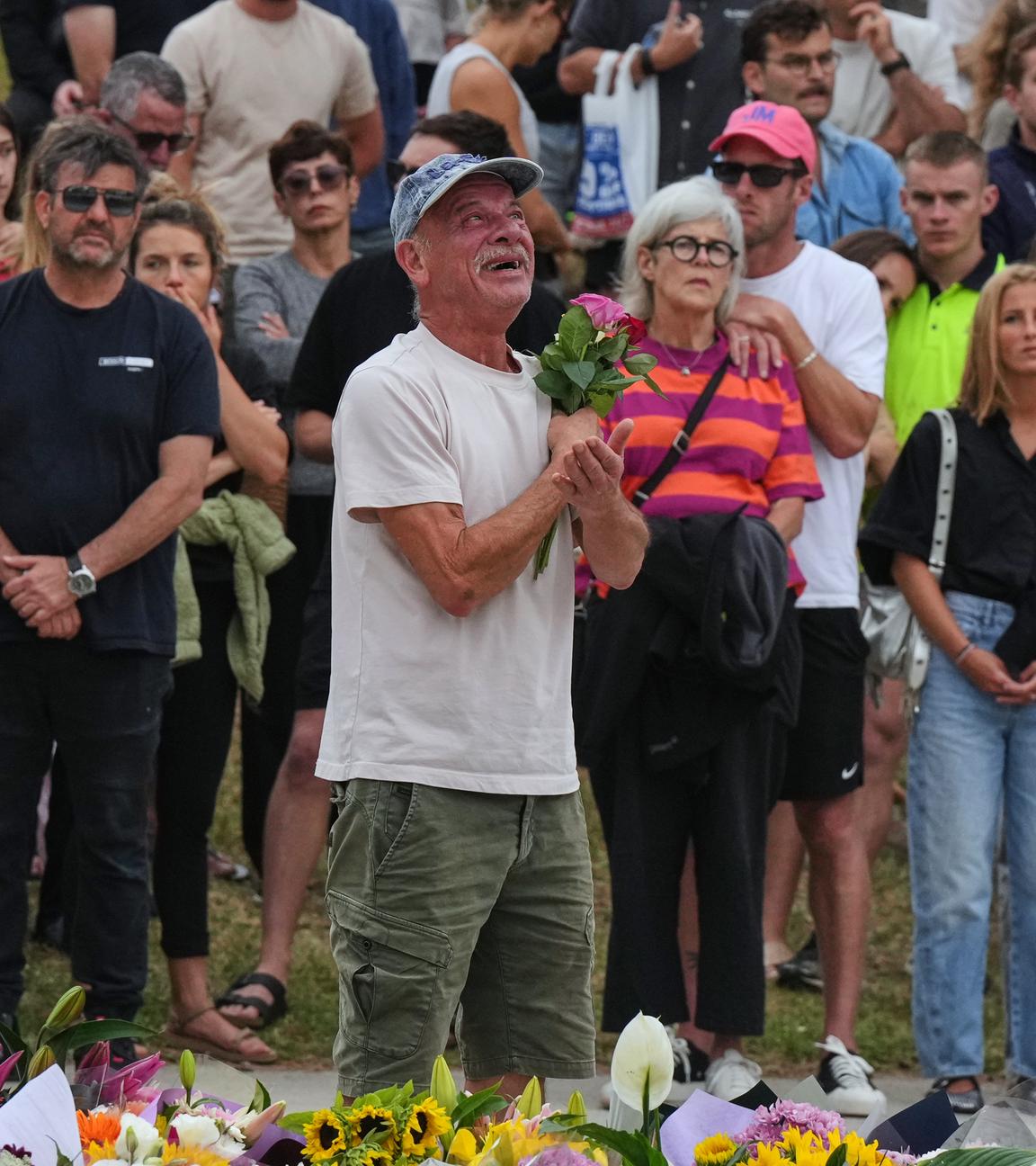 Ein Mann legt vor dem Bondi Pavilion am Bondi Beach in Sydney Blumen für die Opfer nieder