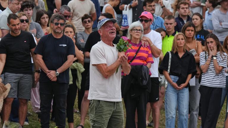 Ein Mann legt vor dem Bondi Pavilion am Bondi Beach in Sydney Blumen für die Opfer nieder