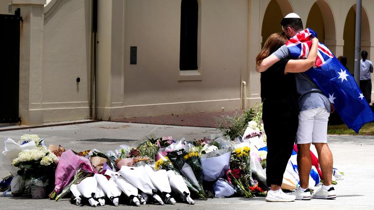 Ein Paar legt Blumen an einer Gedenkstätte für die Opfer der Schießerei vor dem Bondi Pavilion am Bondi Beach in Sydney nieder, am 15.12.2025, einen Tag nach der Schießerei.
