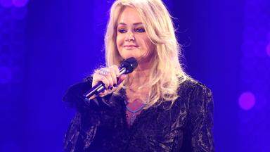 Bonnie Tyler steht mit einem Mikrofon auf der Bühne. Sie ist schwarz gekleidet.