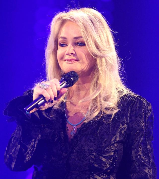 Bonnie Tyler steht mit einem Mikrofon auf der Bühne. Sie ist schwarz gekleidet.