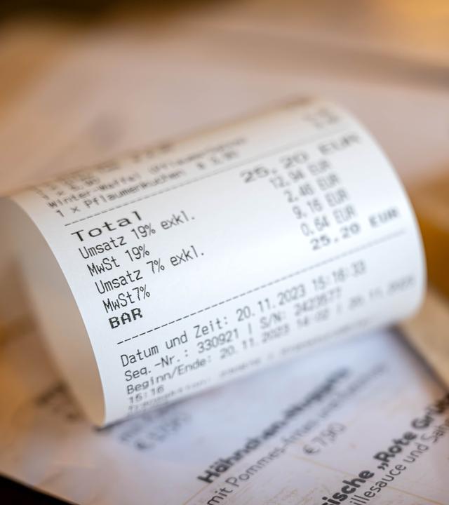 Eine Rechnung mit Umsatzsteuer und Mehrwertsteuer liegt auf der Speisekarte eines Restaurants.