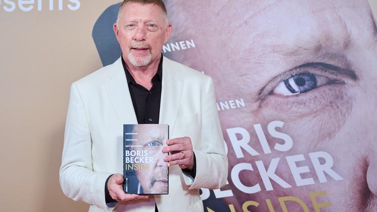 Boris Becker hält sein neues Buch in die Kamera.