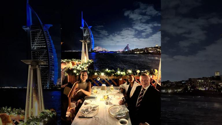 Boris Becker und seine Familie sitzen ellegant gekleidet an einem Essenstisch auf einer Terasse. Im Hintergrund sieht man die beleuchtete Skyline von Dubai