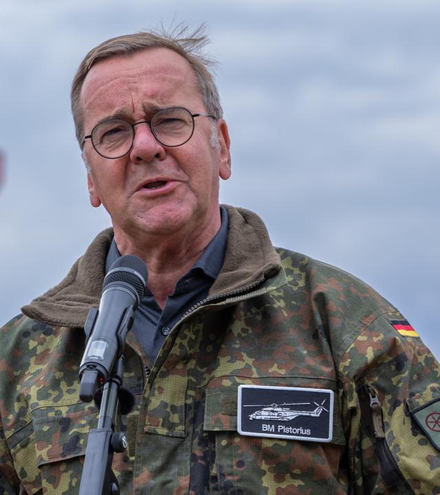 Bundesverteidigungsminister Boris Pistorius spricht vor einem Mikrofon, gekleidet in Bundeswehr-Flecktarn-Jacke.