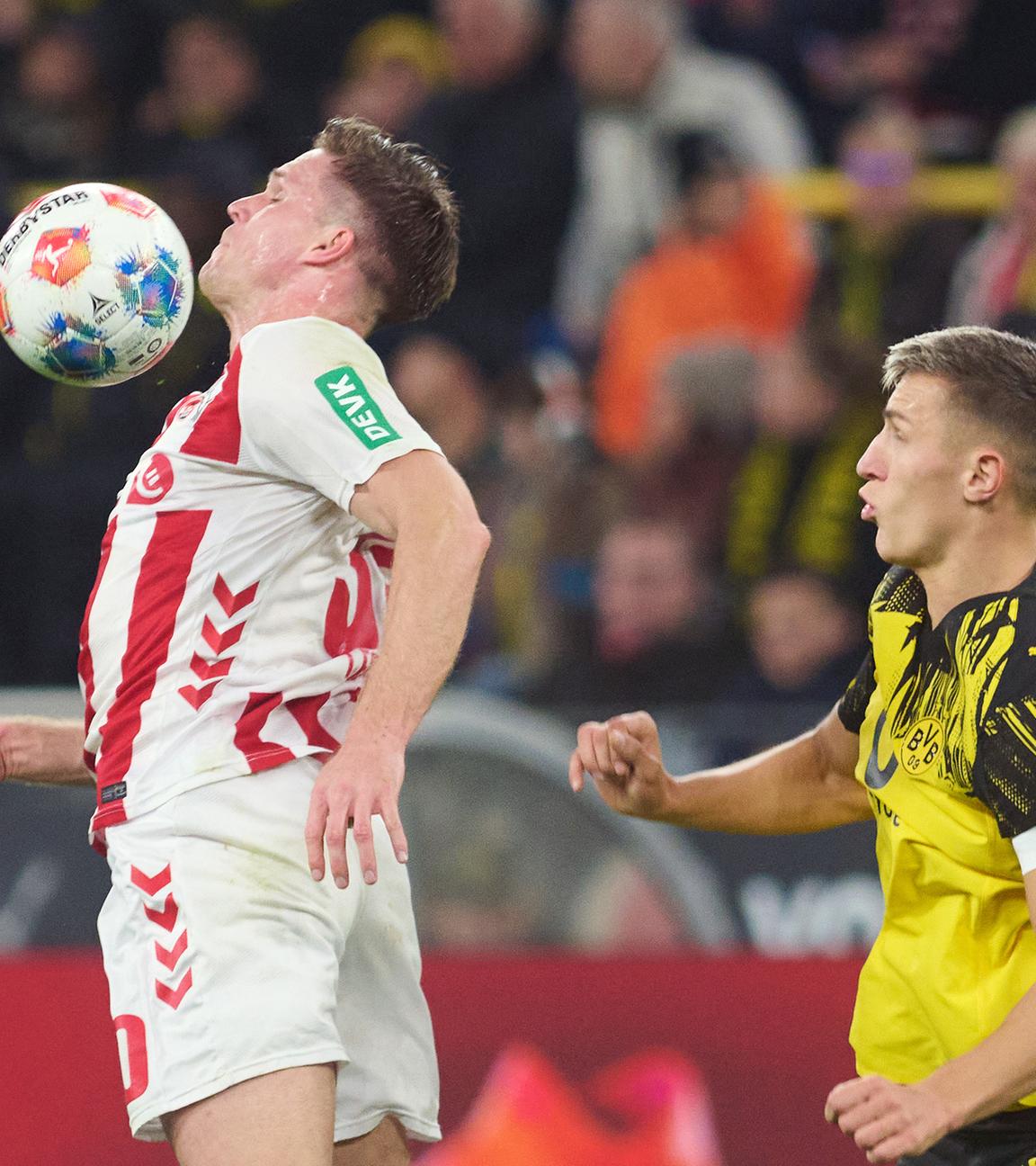 Borussia Dortmund spielt gegen den 1. FC Köln. Bülter (Köln) und Schlotterbeck (BVB) in Aktion. 