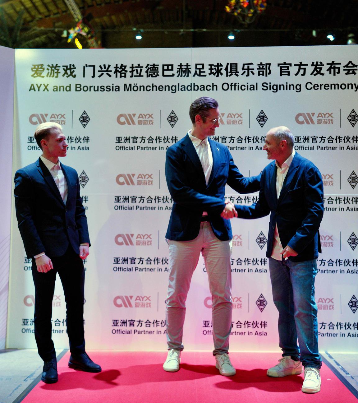 Vertreter von Borussia Mönchengladbach vor einer Werbewand von AYX.