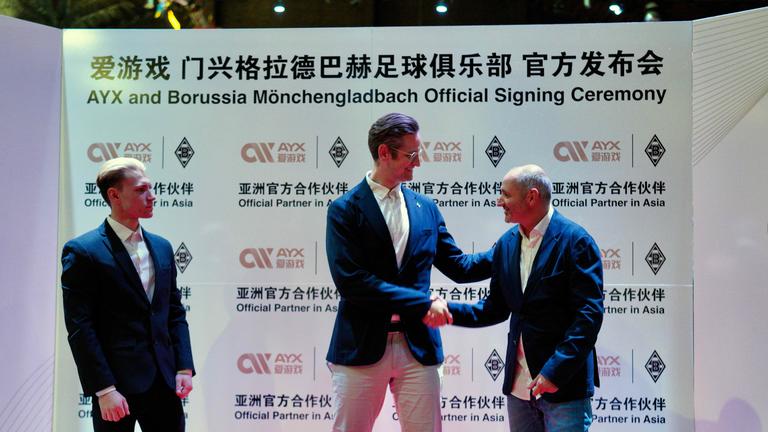 Vertreter von Borussia Mönchengladbach vor einer Werbewand von AYX.