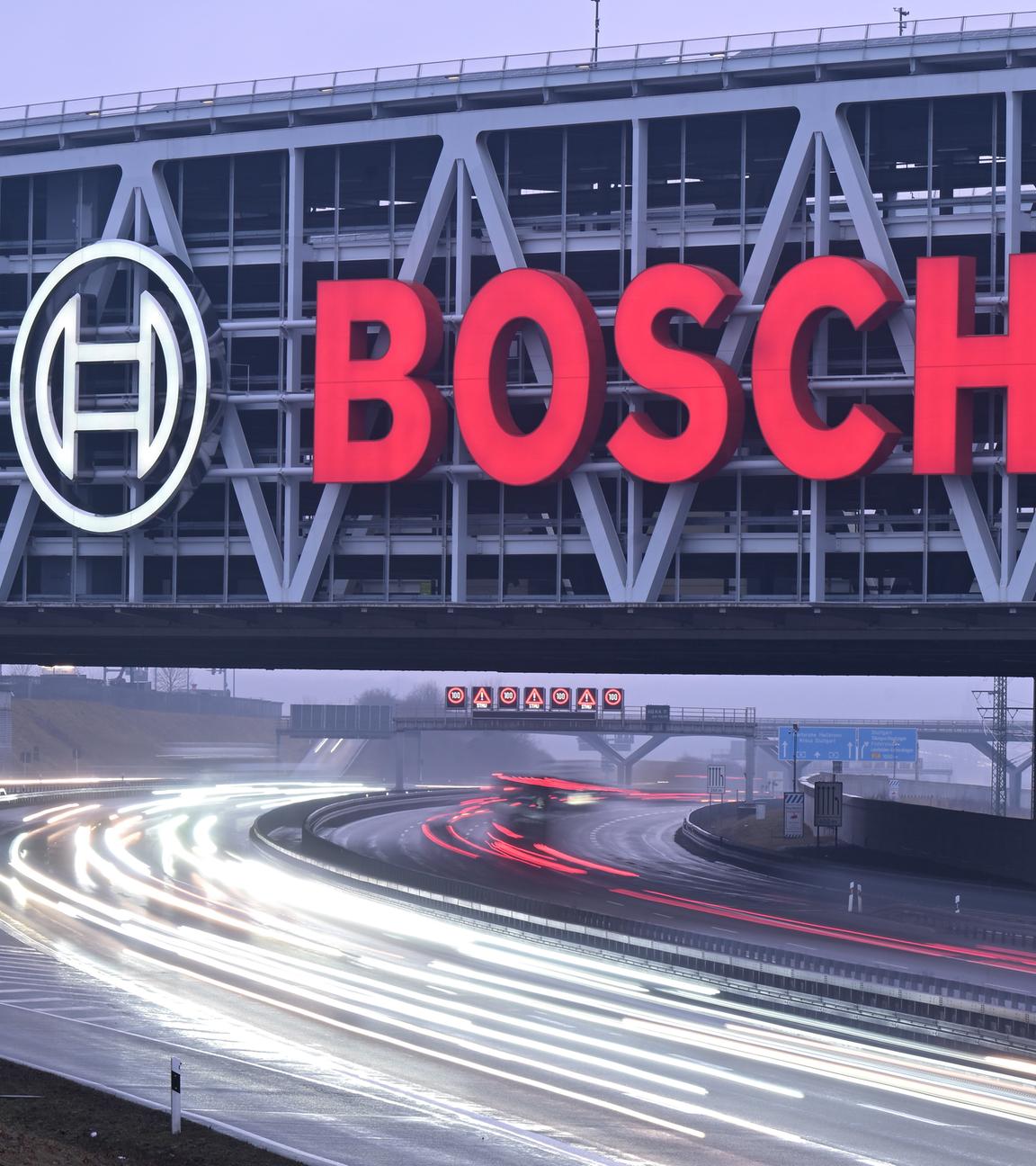 Das Logo des Industriekonzerns Bosch leuchtet an einem Parkhaus über einer Autobahn (Wischeffekt durch Lasngzeitbelichtung). 