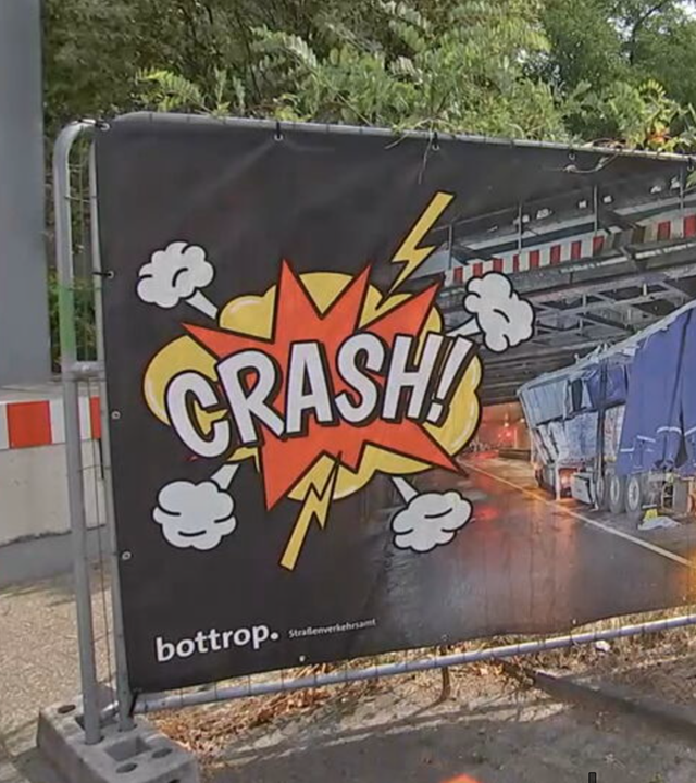 Das Bild zeigt ein Warnschild, das vor der Unfallgefahr einer zu niedrigen Eisenbahnbrücke warnt.