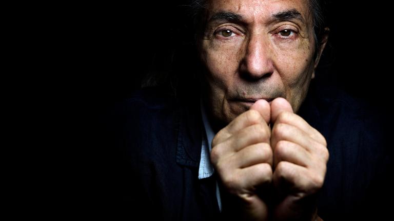 Nahaufnahme des Gesichts eines älteren Mannes der sich die Fäuste vor den Mund hält.