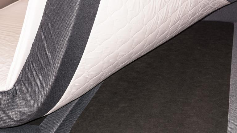 Die Ecke einer Matratze eines Boxspringbetts wird angehoben.