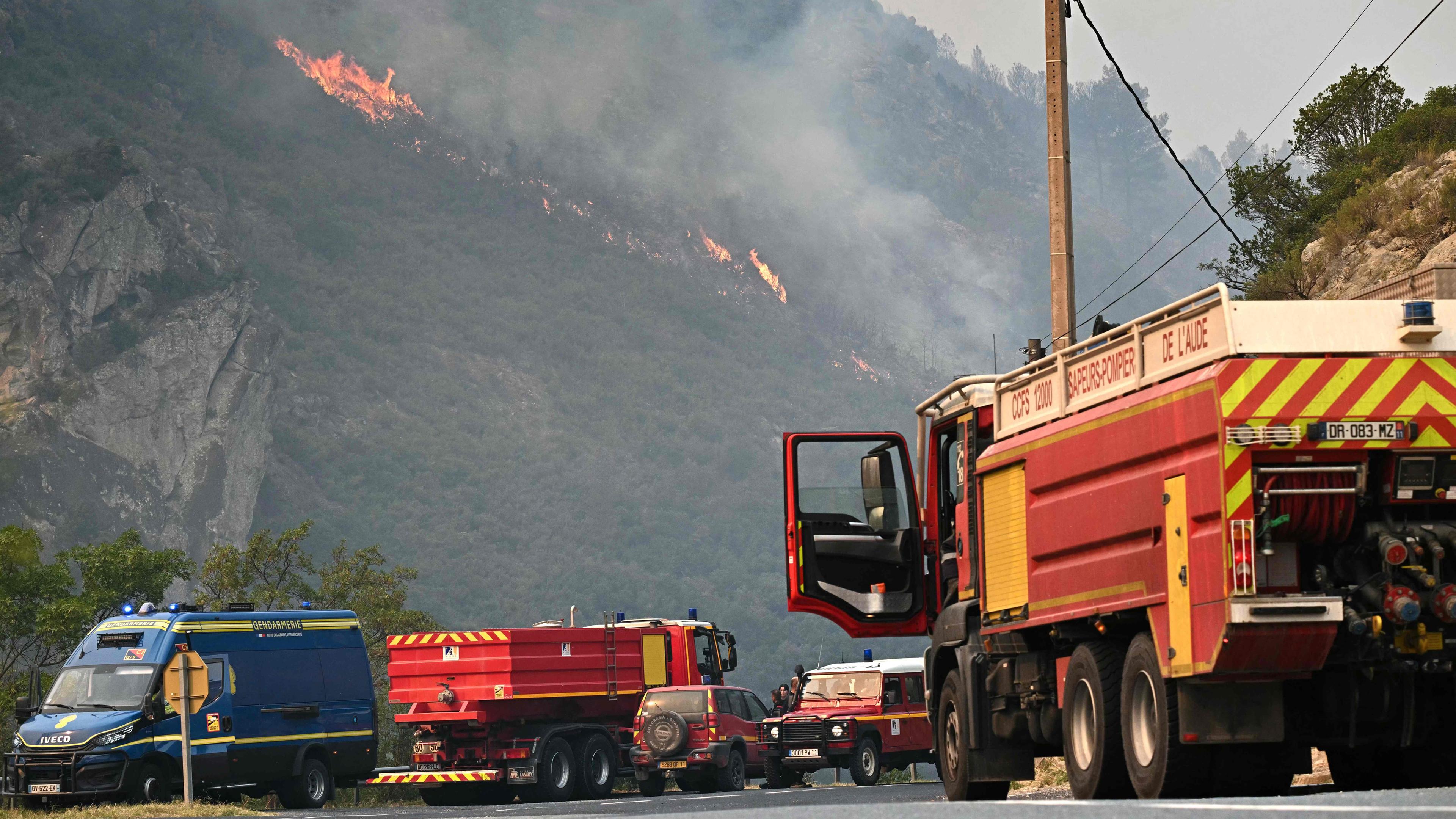 Dieses Foto zeigt französische Feuerwehrfahrzeuge, die am 6. August 2025 vor einem Waldbrand in der Nähe von Fraissé-des-Corbières im Südwesten Frankreichs geparkt sind. 