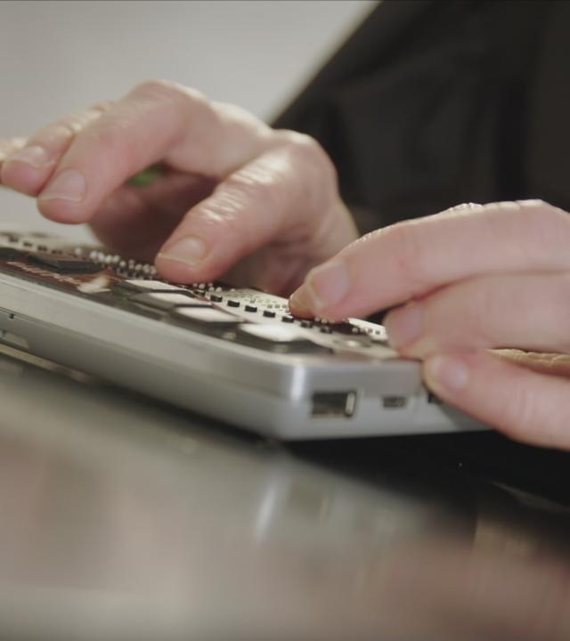Finger, die auf einem Schreibgerät für Brailleschrift tippen