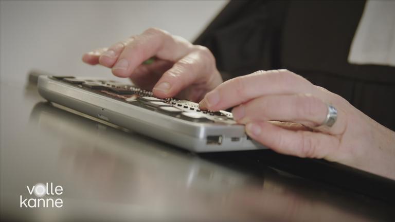 Finger, die auf einem Schreibgerät für Brailleschrift tippen