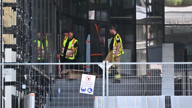 Rettungskräfte stehen vor dem OXY-Gebäude am Place De Brouckere.