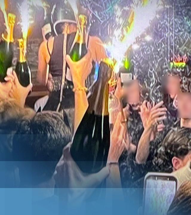 Gäste der Bar "Le Constellation" in Crans-Montana feiern mit großen Wunderkerzen und Sektflaschen.