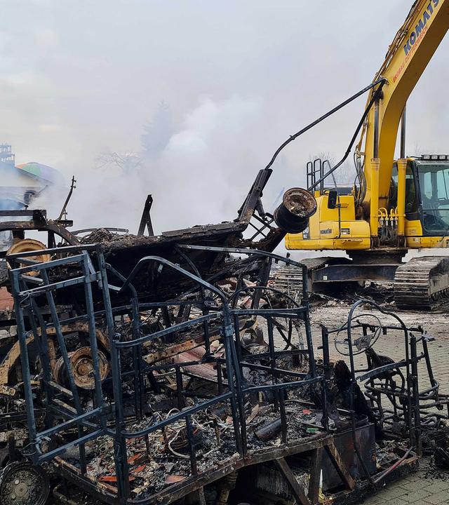 Eine von Feuer geschwärzte Metallkonstruktion steht neben einem Bagger, aufgenommen am 17.03.2025