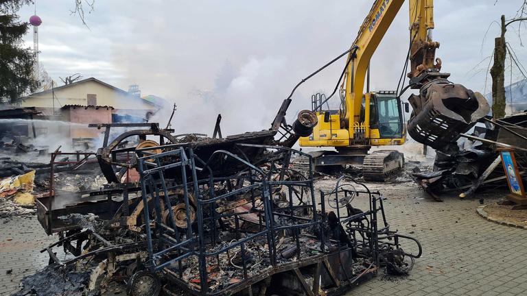 Eine von Feuer geschwärzte Metallkonstruktion steht neben einem Bagger, aufgenommen am 17.03.2025