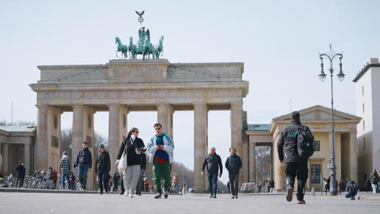 Mehrere Menschen laufen vor dem Brandenburger Tor in Berlin.