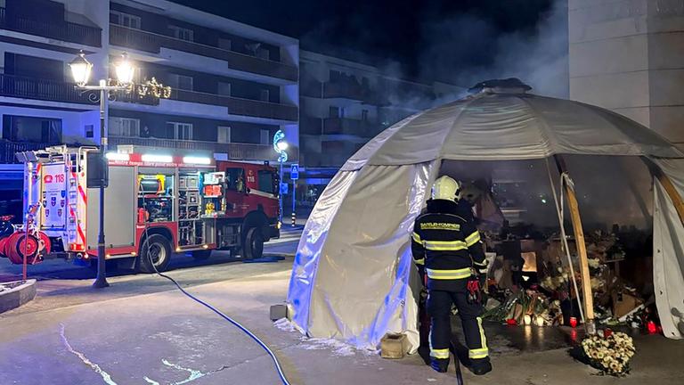 Dieses Foto, das von der Kantonspolizei Wallis am 08.02.2026 aufgenommen und veröffentlicht wurde, zeigt Feuerwehrleute bei der Löschung eines Brandes an einer Gedenkstätte vor der Bar „Le Constellation“ zu Ehren der Opfer des tödlichen Brandes, der die Bar in Crans-Montana in der Silvesternacht verwüstet hatte.