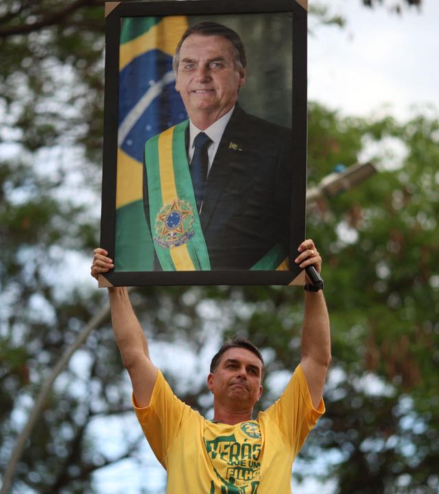 Brasiliens Präsidentschaftskandidat Flávio Bolsonaro hält das Bild seines Vaters, dem ehemaligen und verurteilten Präsidenten Jair Bolsonaro, hoch.