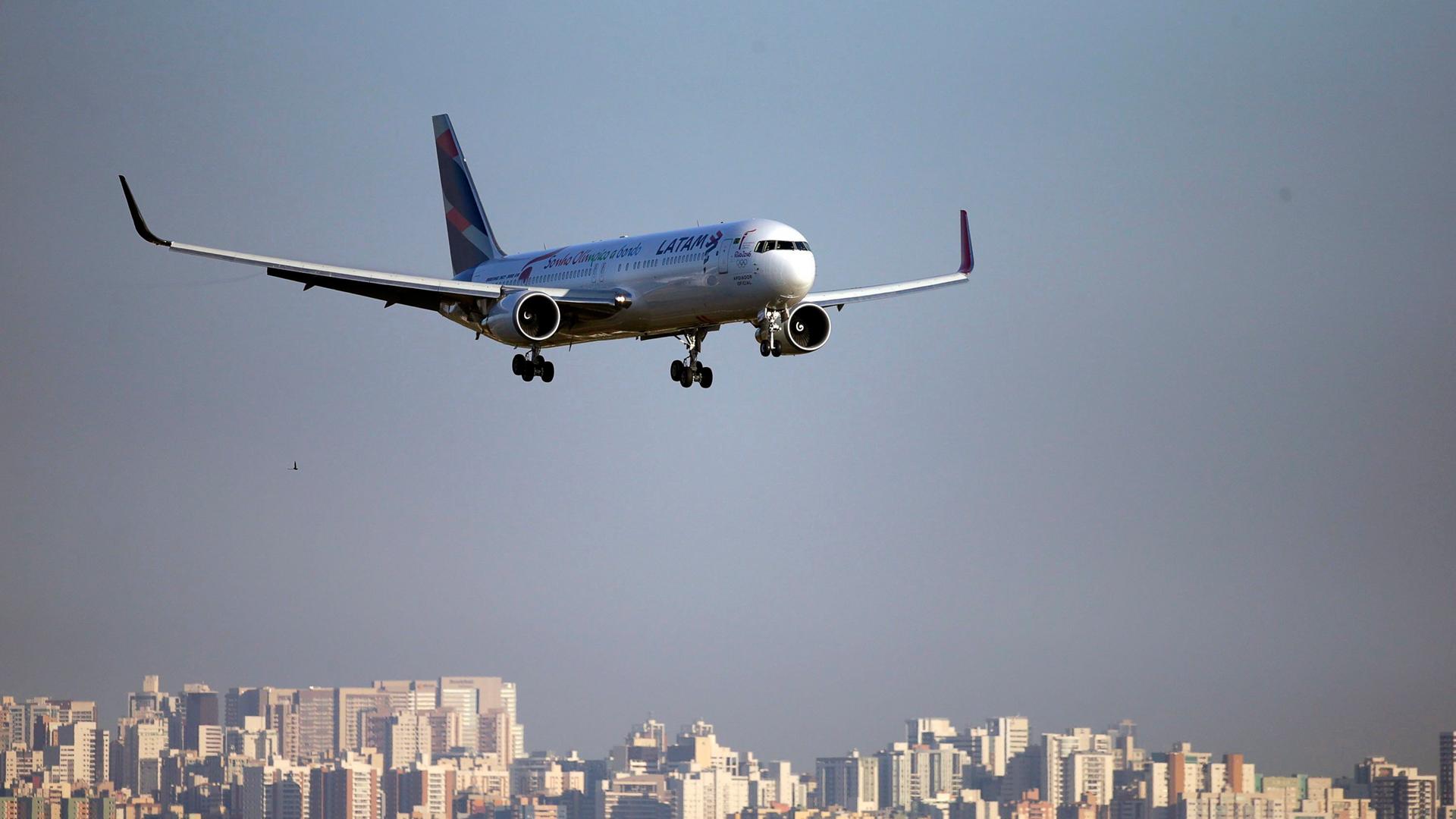 Ein Flugzeug fliegt im wolkenlosen Himmel über eine Großstadt.