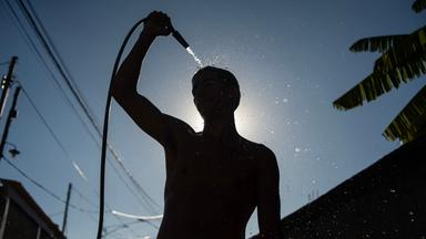 Ein Mann erfrischt sich mit einem Wasserschlauch während einer Hitzewelle in der brasilianischen Stadt Rio de Janeiro.