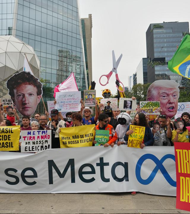 Demonstranten protestieren vor dem Hauptsitz von Meta in São Paulo gegen das Unternehmen. Sie halten ein Banner mit der Aufschrift „Meta, mischt euch nicht ein“.