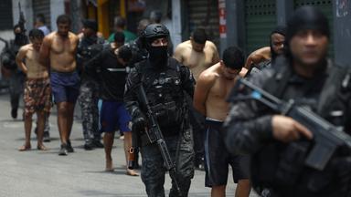 Polizisten bewachen eine Gruppe von Menschen während eines Einsatzes in Rio de Janeiro, Brasilien