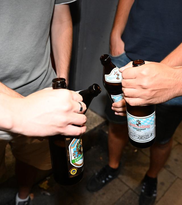 Feiernde prosten in der Schellingstraße mit Bier an