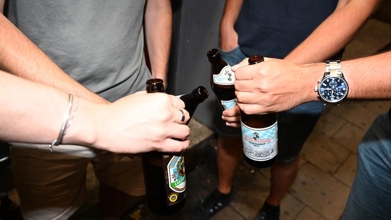 Feiernde prosten in der Schellingstraße mit Bier an