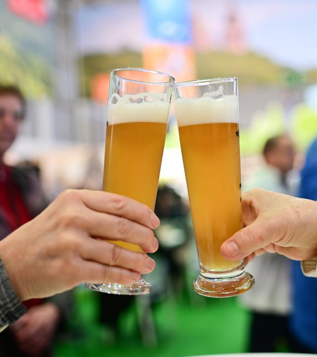 Zwei Personen stoßen mit Bier an