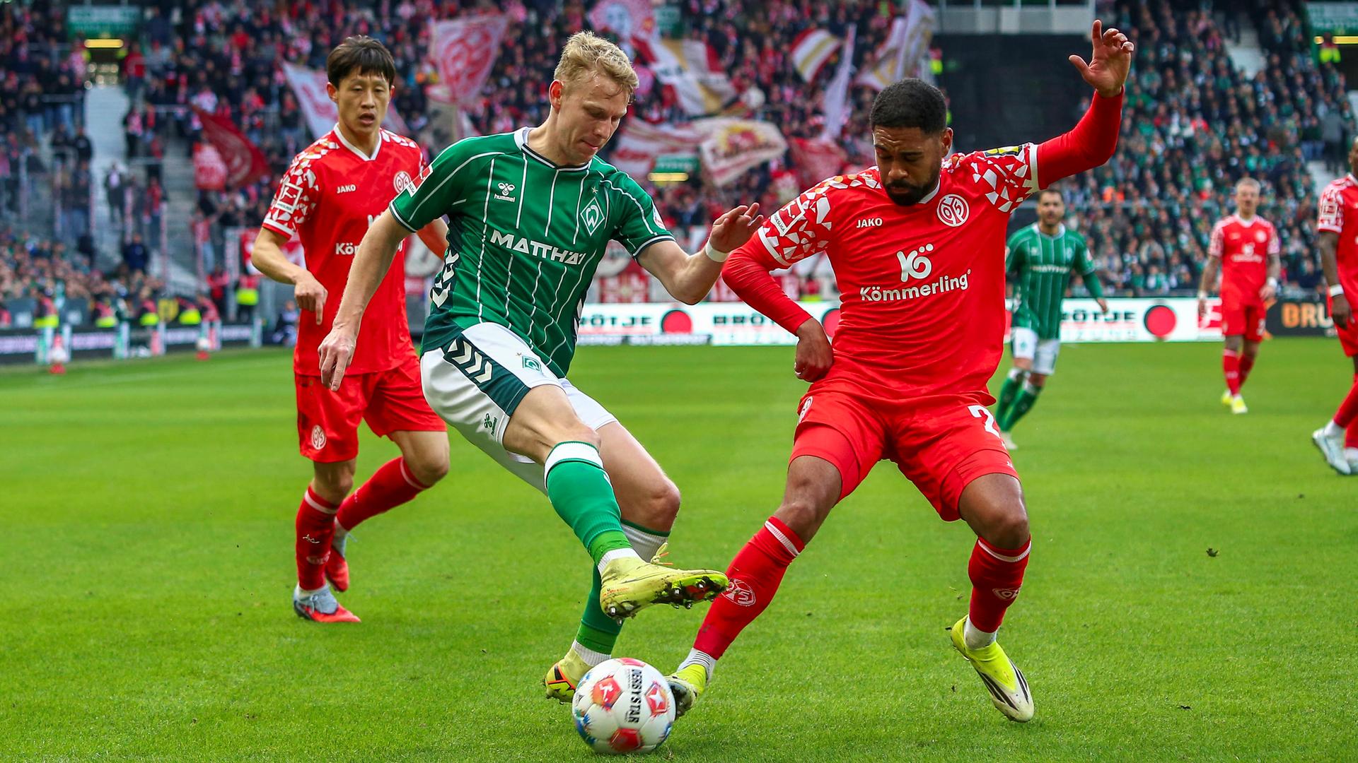 Marco Grüll (SV Werder Bremen) und Phillipp Mwene (1. FSV Mainz 05) kämpfen am 15.03.2026 in Bremen um den Ball. 