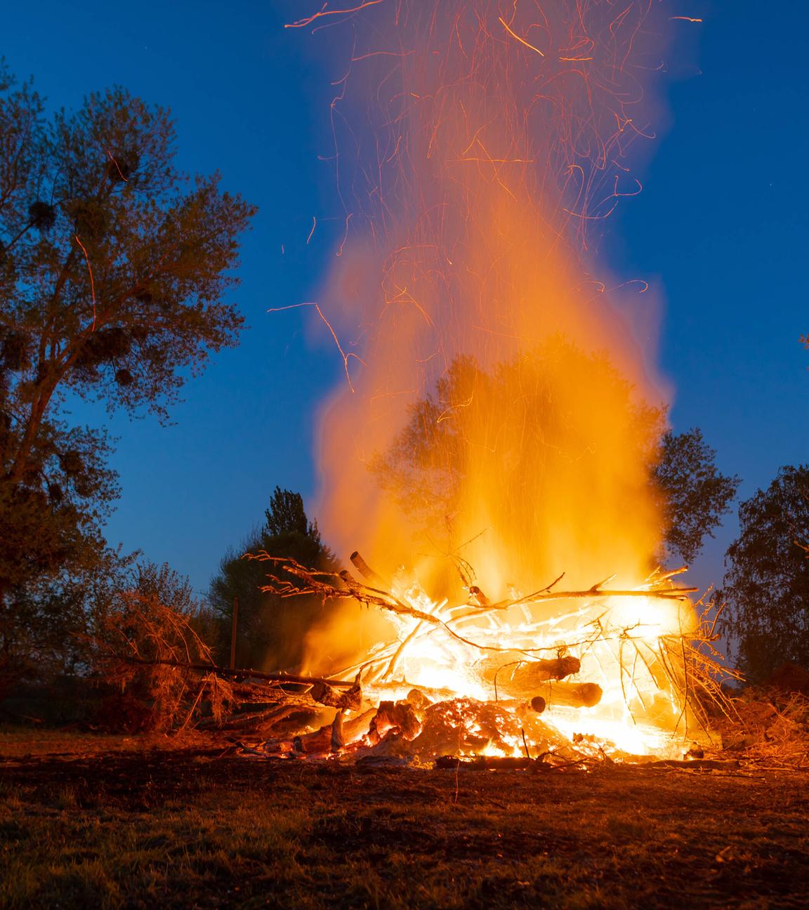 Ein großes brennendes Osterfeuer vor blauem Abendhimmel.