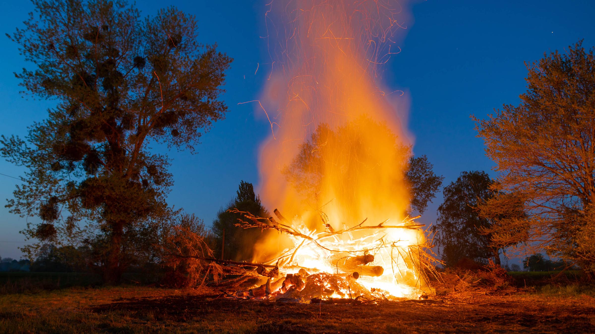Ein großes brennendes Osterfeuer vor blauem Abendhimmel.
