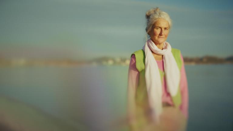 Auf dem Foto ist Britta zu sehen, eine Dame Ende 50, sie steht vor einem See.
