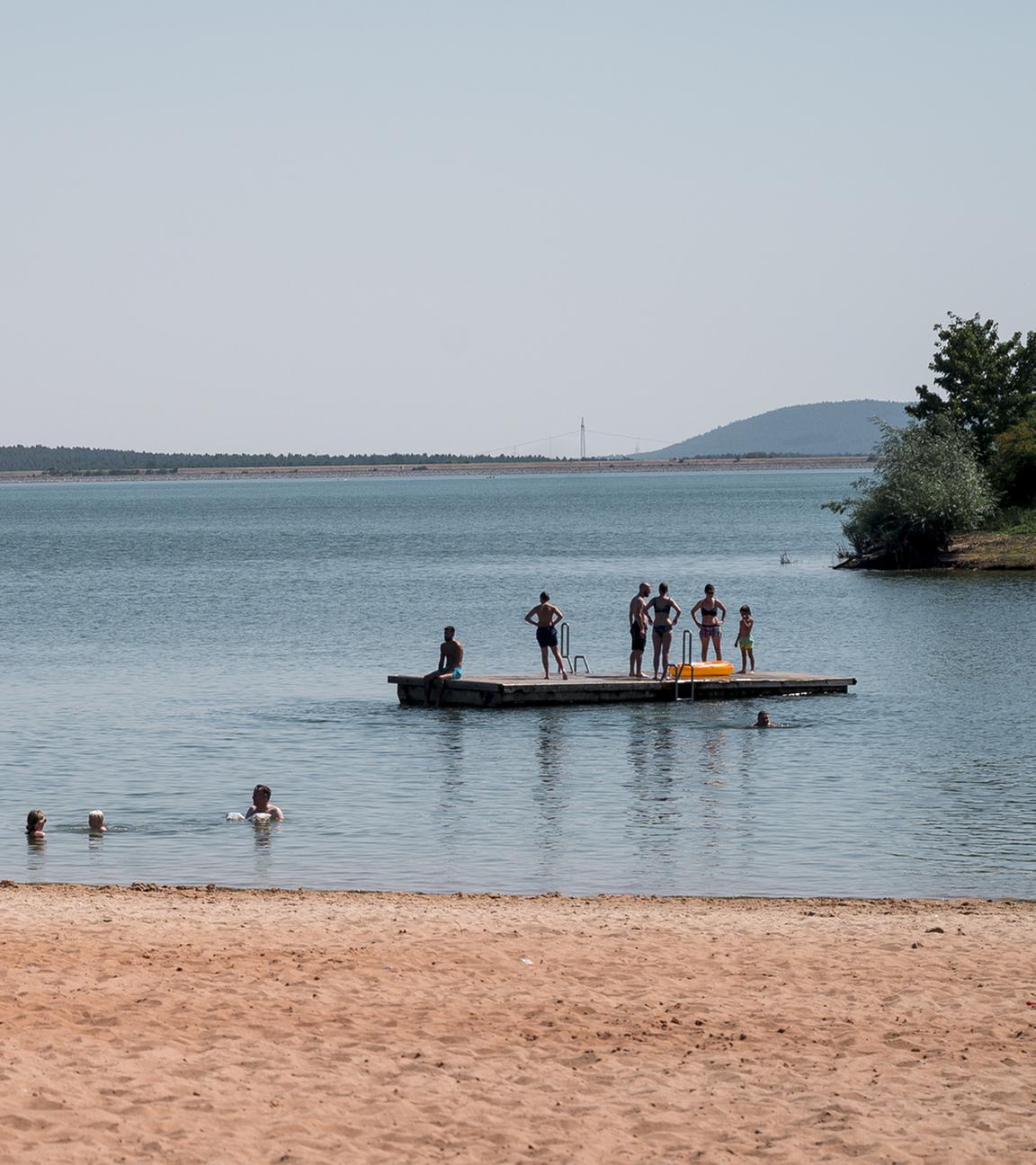  Badegäste sind im Wasser und auf einem schwimmenden Floß